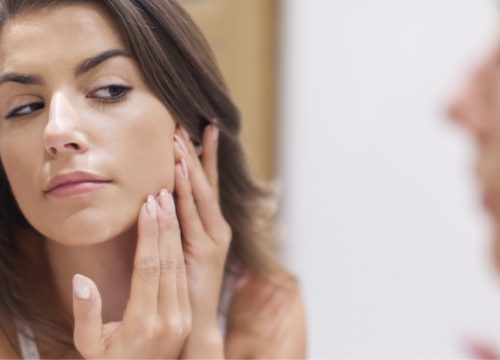Woman looking at her skin for acne and acne scarring